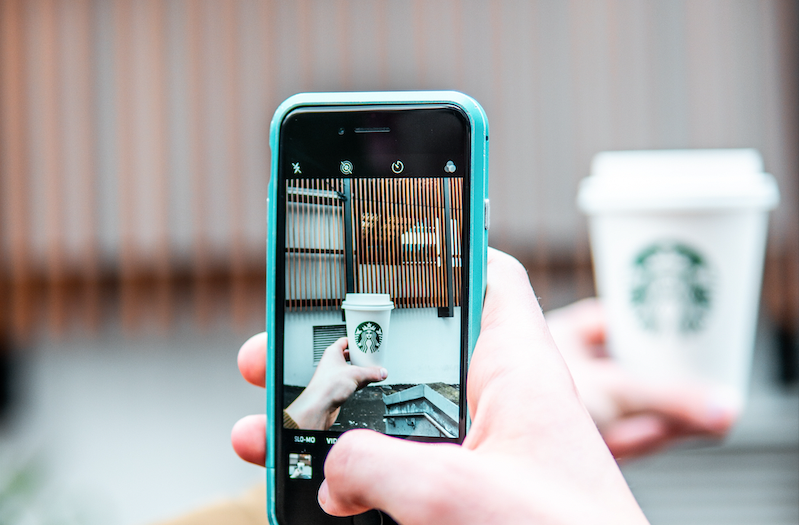 Advocate using iPhone to take a photo of a Starbucks to-go cup